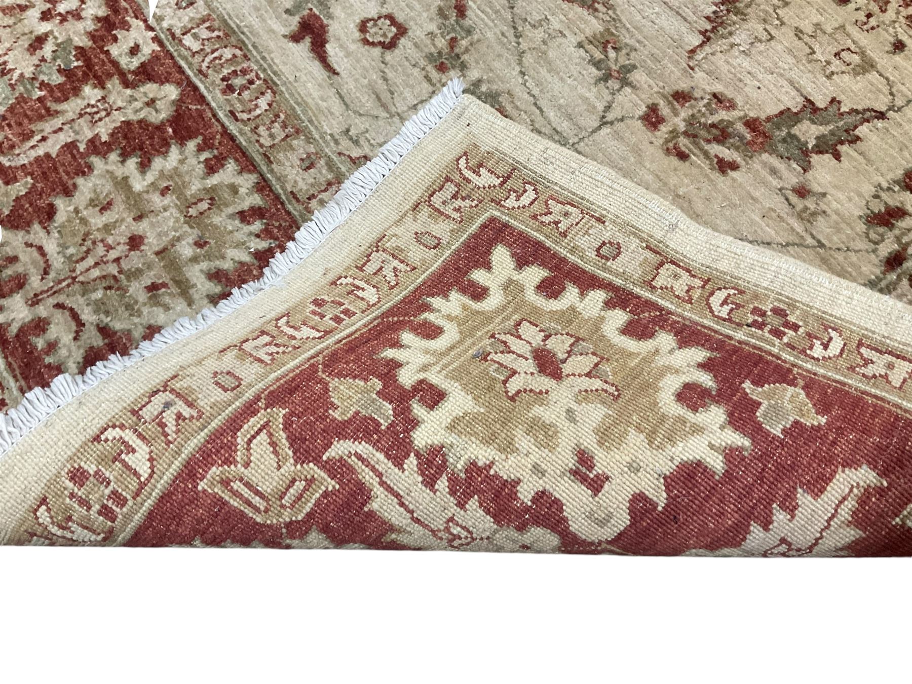 Persian Zeigler beige ground rug, the field decorated with large palmette motifs interconnected with scrolling foliate and branches, enclosed by a wide crimson guard band with repeating stylised plant motifs