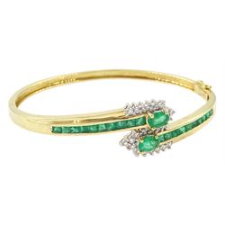 14ct gold emerald and diamond crossover bangle, two oval cut emeralds with round brilliant...