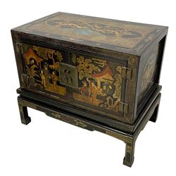 Pair of early 20th century Chinese ebonised and lacquered wood cabinets, the top decorated with dragons over lapping waves within a gilt patterned panel, the surrounding band decorated with Chinese symbols and flowerheads, enclosed by two doors each with village scenes with pagodas, figures and trees, the panelled sides decorated with a figure riding a dragon on stands with gilt decorated 