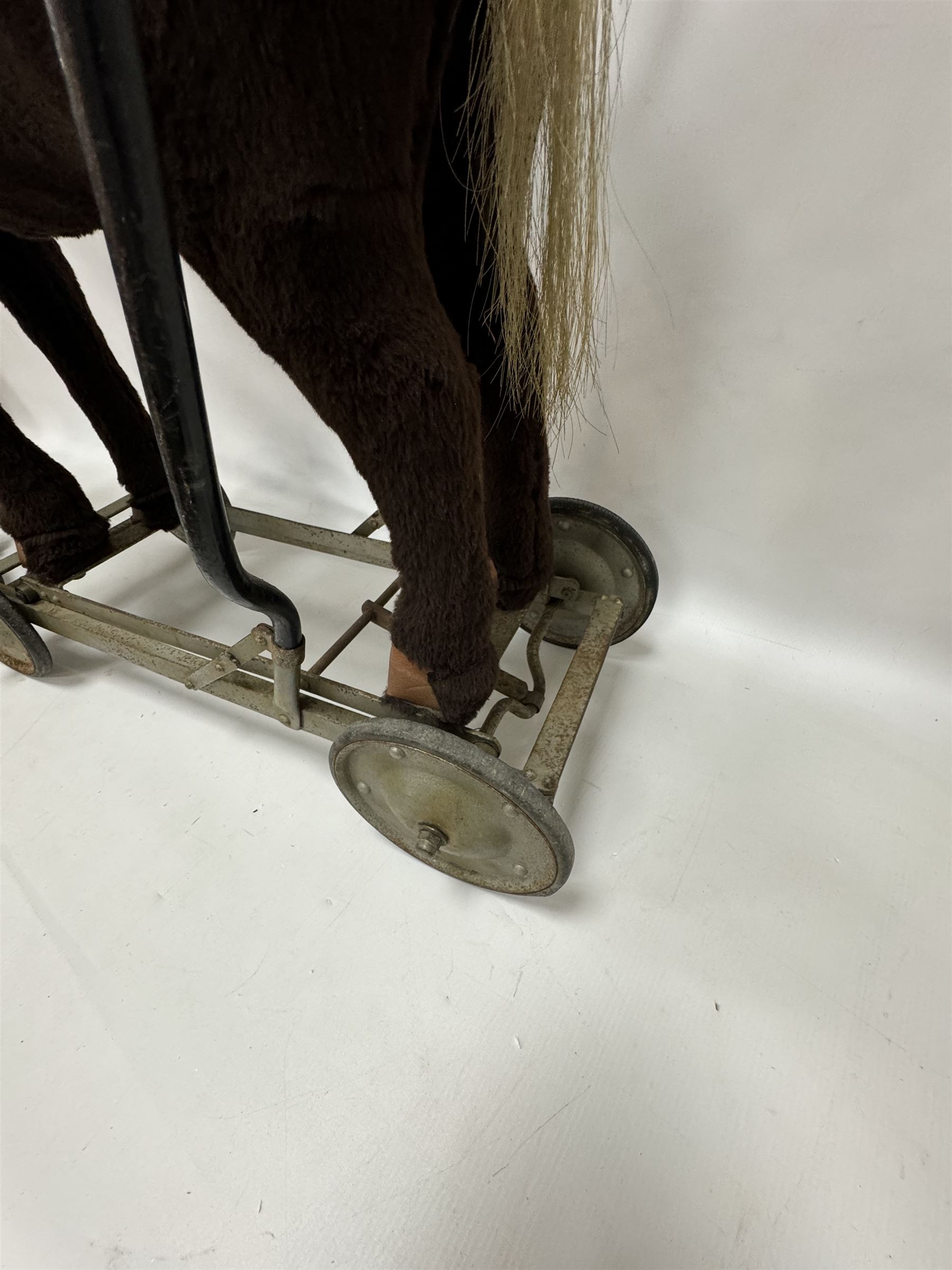 1920s/30s Panurge Pets push-a-long horse, with brown mohair body and white face, horse hair mane and tail and leather hooves, mounted upon a metal with rubber and metal wheels, including handle H71cm