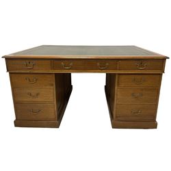 Late 19th century twin pedestal oak partner's desk, rectangular top with inset green leather writing surface, fitted with nine graduating drawers to each side, the rear drawers enclosed by panelled cupboards