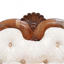 Victorian mahogany frame settee, shaped cresting rail with fan carved cresting, upholstered in buttoned cream fabric with repeating floral pattern, low serpentine seat, shaped and pierced bracket feet, on brass castors 