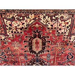 Persian Heriz red ground carpet, large central eight point medallion with projecting palmettes surrounded by small geometric motifs, decorated profusely with hooks, rosettes and animals, the busy border decorated with stylised foliate motifs within guard stripes 