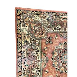 Persian design peach ground carpet, central floral medallion surrounded by scrolling foliage, decorated all over with stylised plant motifs, floral design repeating border