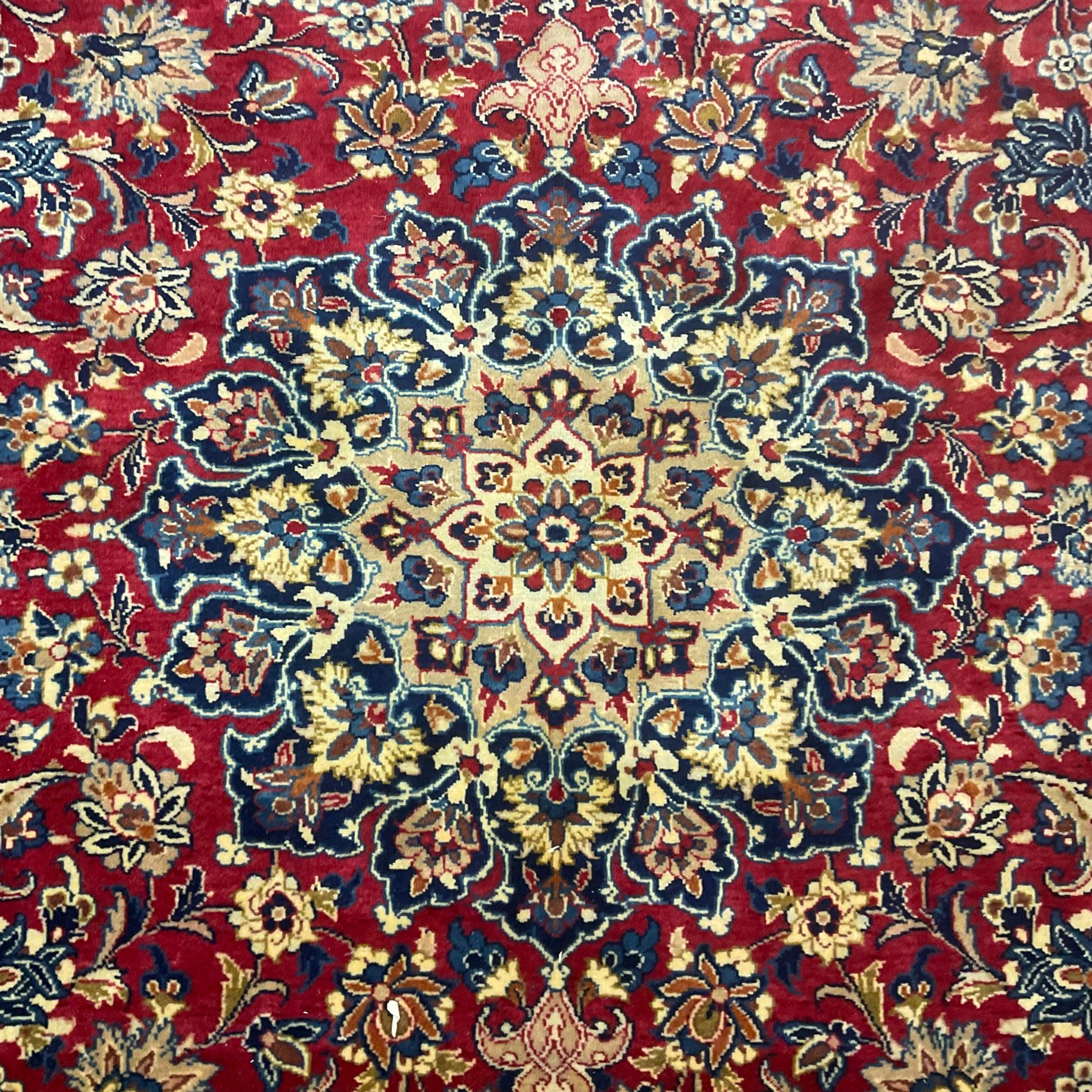 Persian Kashan red ground carpet, the field decorated with central medallion surrounded by trailing branches and stylised plant motifs, blue ground border with scrolling floral design 