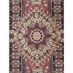 Persian Heriz design red ground carpet, the field decorated with a central star-shaped medallion surrounded by geometric floral motifs and angular vine patterns, the spandrels highlighted with palmette designs, the main border featuring a series of stylised rosettes and leaves against a dark blue ground, enclosed by multiple guard stripes with alternating floral and geometric motifs