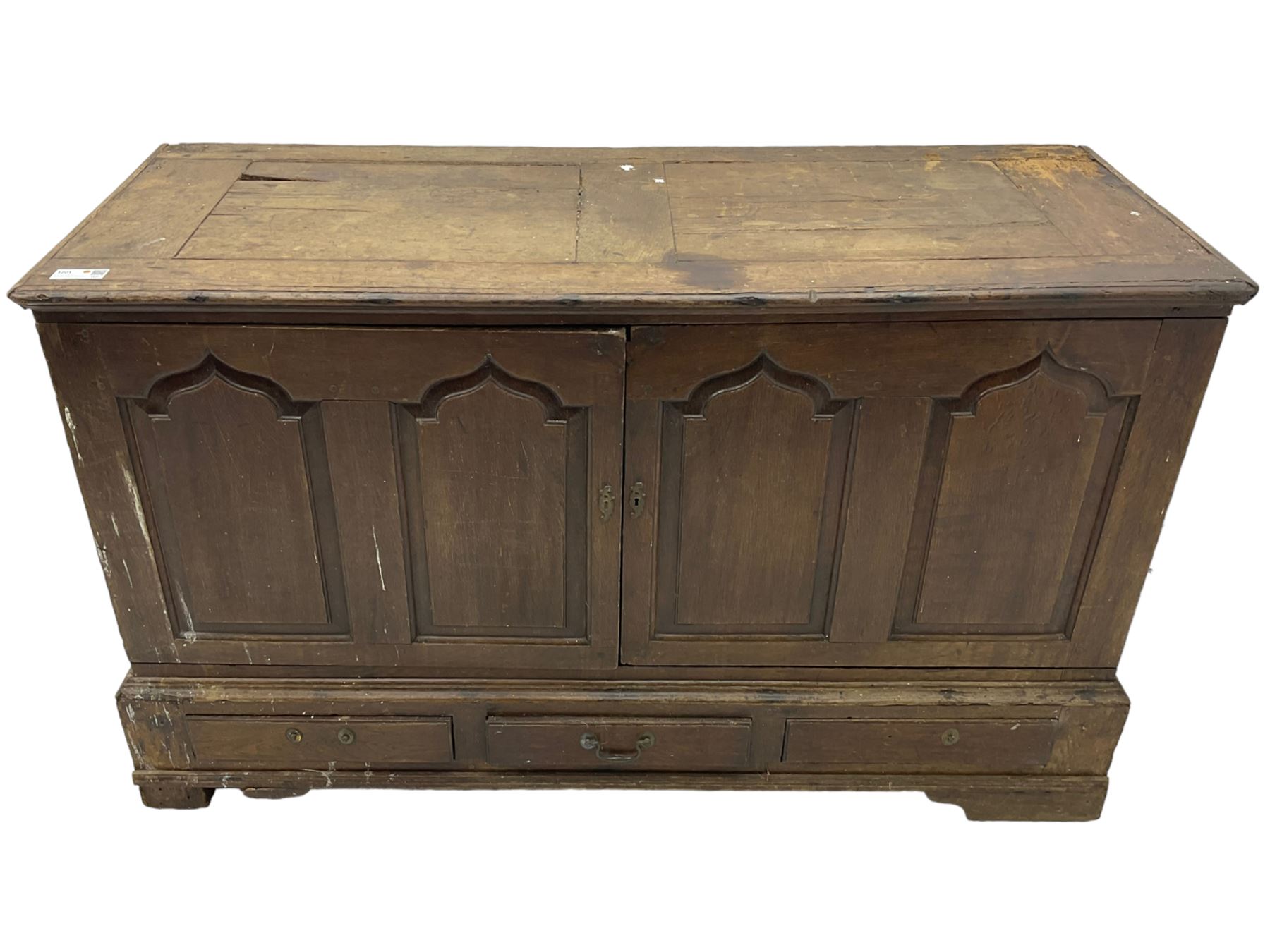 Georgian oak converted mule chest, rectangular plank top over two cupboards with arched Gothic motif panels enclosing storage area with shelves, the base with three drawers with pull handles, on shaped bracket feet