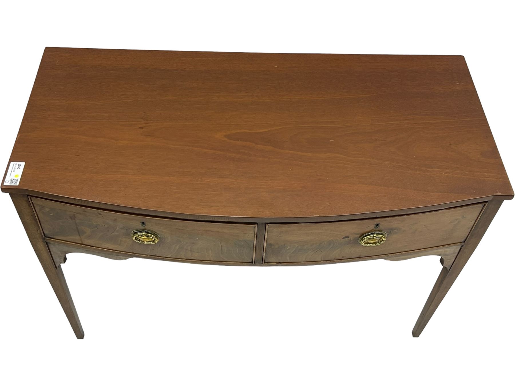 19th century mahogany bow-front serving table, fitted with two cock-beaded drawers with oval pressed brass handles decorated with urns, on square tapering supports 