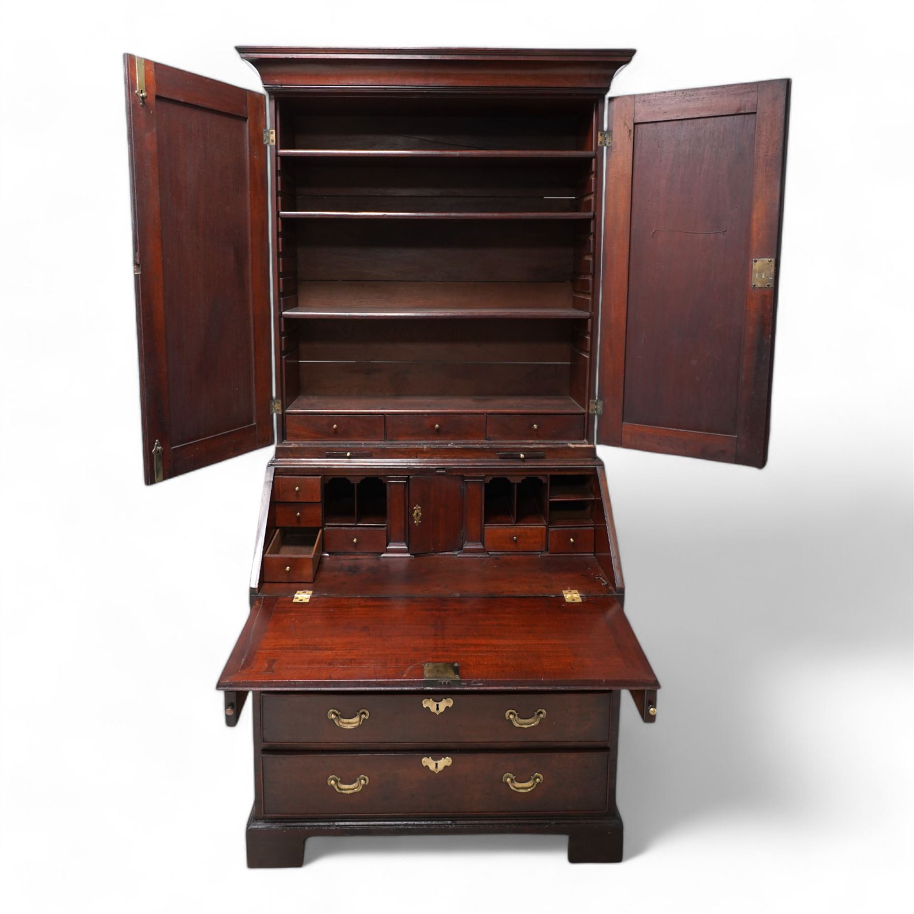 18th century mahogany bureau bookcase, cavetto moulded cornice over two panelled doors and candle slides, the interior fitted with adjustable shelves and small drawers, moulded fall front enclosing pigeonholes, small drawers and cupboard, four long graduating cock-beaded drawers below with shaped brass handles, on bracket feet 