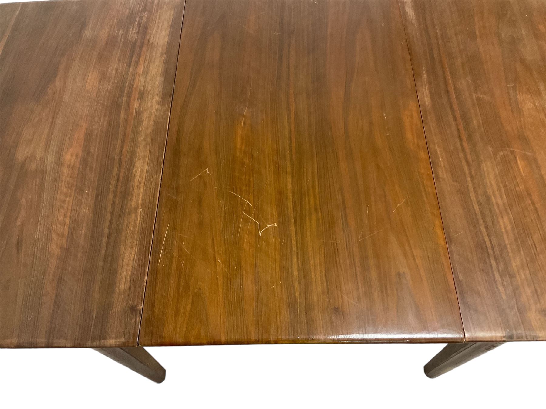 Mid-20th century teak extending dining table, rectangular top with rounded corners, raised on shaped tapering supports united by X-stretcher, with additional leaf