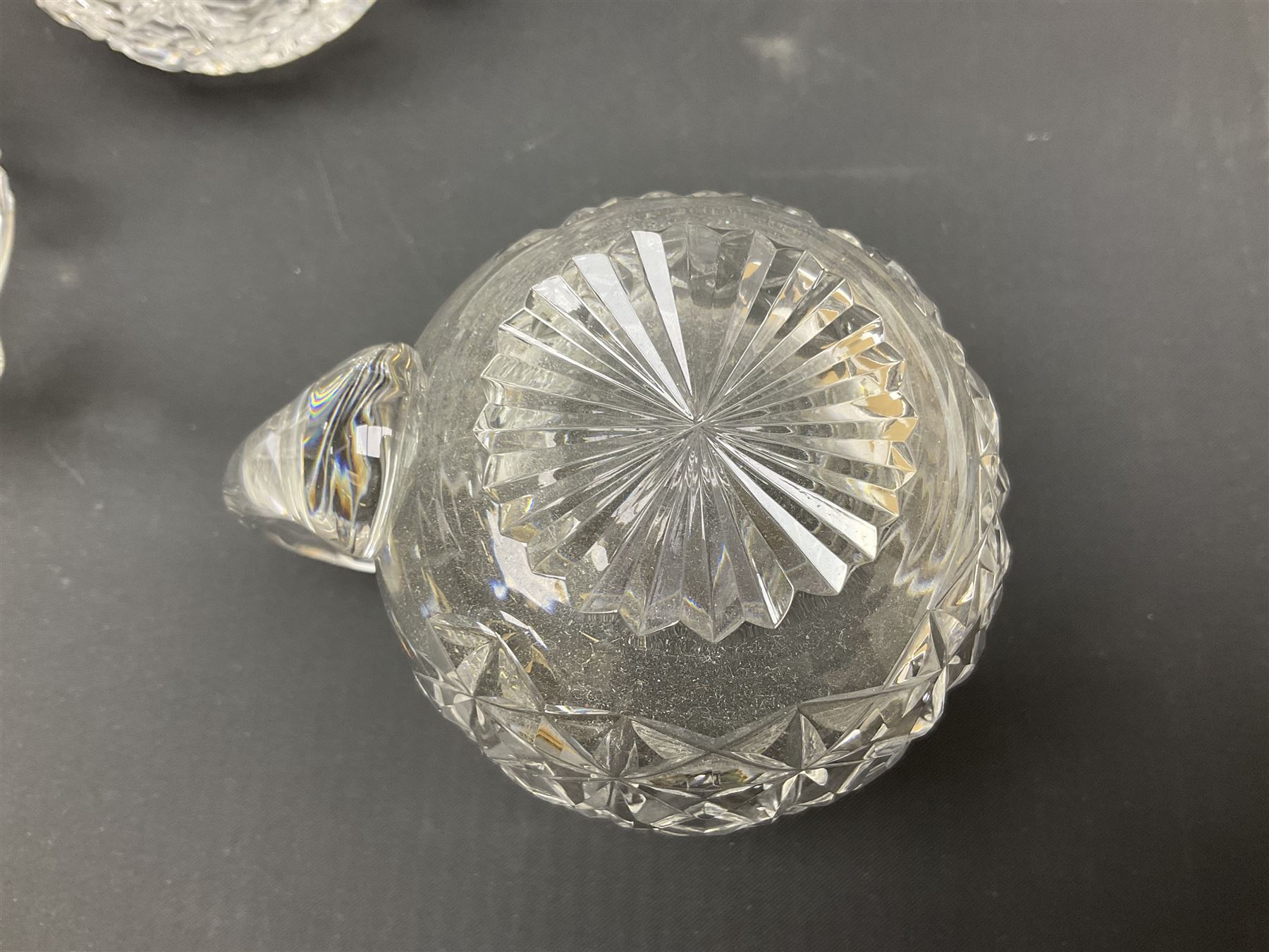 Large Stuart crystal pedestal punch bowl, of circular form, the rim with engraved floral decoration, upon spreading circular foot with radial cut decoration, with seven matching Stuart crystal drinking glasses, each with a C handle, each acid signed beneath, bowl H20cm