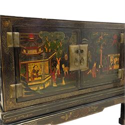 Pair of early 20th century Chinese ebonised and lacquered wood cabinets, the top decorated with dragons over lapping waves within a gilt patterned panel, the surrounding band decorated with Chinese symbols and flowerheads, enclosed by two doors each with village scenes with pagodas, figures and trees, the panelled sides decorated with a figure riding a dragon on stands with gilt decorated 