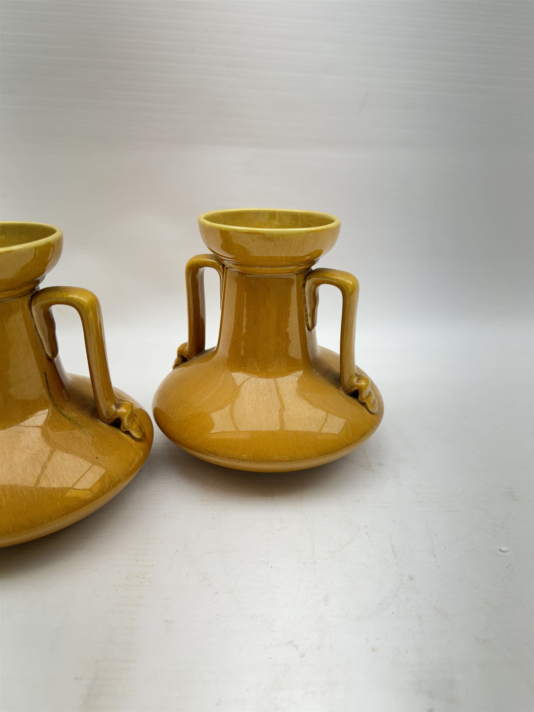 Christopher Dresser for Linthorpe Pottery, pair of twin handled vases, ochre glaze, H14cm