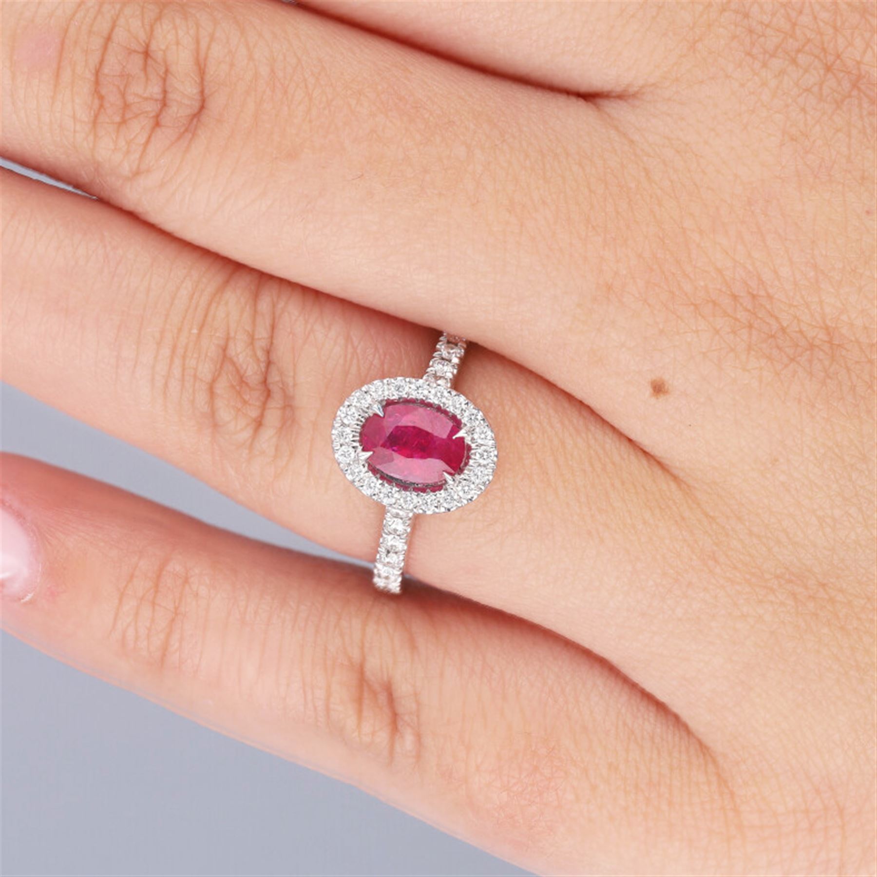 18ct white gold oval cut ruby and round brilliant cut diamond cluster ring, with diamond set shoulders, hallmarked, ruby approx 0.80 carat, total diamond weight 0.37 carat 