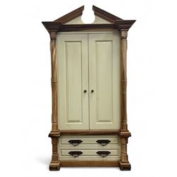 Hardwood and cream painted kitchen larder cupboard, sloped pediment over two panelled doors, the interior fitted with slides, drawers and storage shelves, two long drawers below, mounted by turned pilasters, on metal bound moulded plinth base