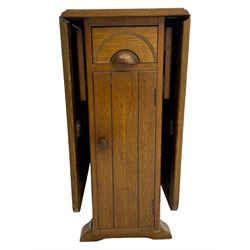 Early 20th century oak drop-leaf table, in the style of Harris Lebus, featuring rectangular top over central pedestal base, with two drawers and two cupboards, on gateleg supports