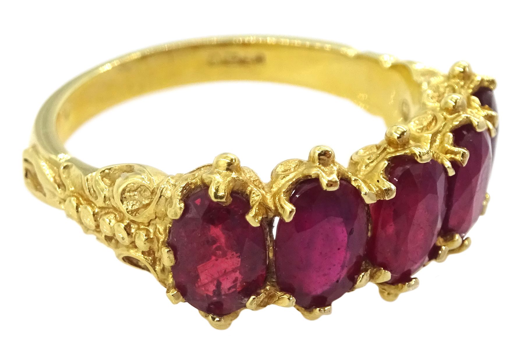 18ct gold five stone oval cut glass-filled ruby ring, with scroll design shoulders, London 2005