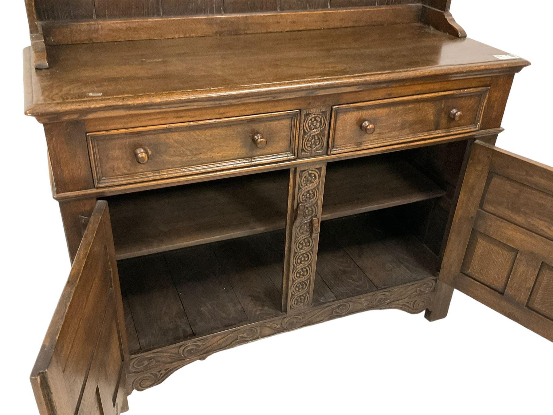 Georgian design oak dresser, two-tier plate rack with shaped aprons, the base fitted with two fielded moulded drawers, over two panelled cupboards carved with scrolling acanthus leaves, with guilloche carved central upright, on stile feet