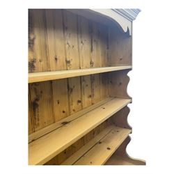 Large traditional pine dresser, shaped cornice over three open shelves, base fitted with four drawers above four panelled cupboards, each with turned wooden knobs, on plinth base