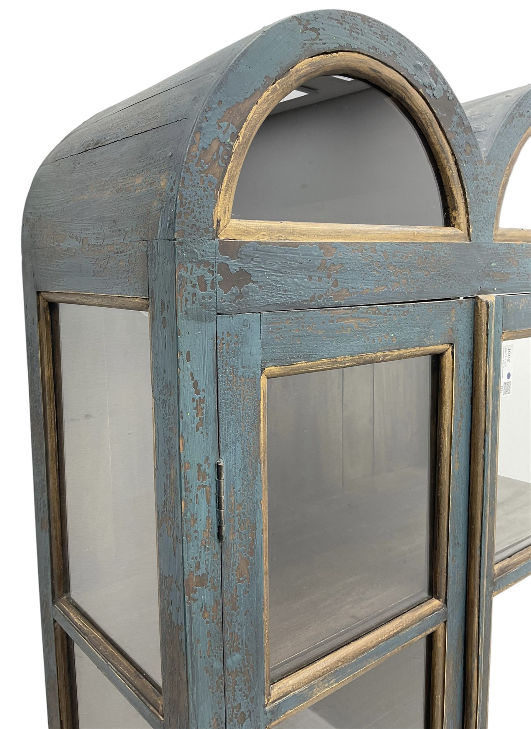 Tall painted glazed display cabinet, double arched top over two glazed doors, fitted with three shelves, in rustic blue paint finish, on cabriole feet