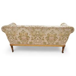 19th century gilt wood and gesso settee, upholstered in repeating floral pattern fabric, rolled arms decorated with trailing bead moulding and acanthus leaf, the seat rail with flower head band, on twist turned and foliate carved feet with brass castors 