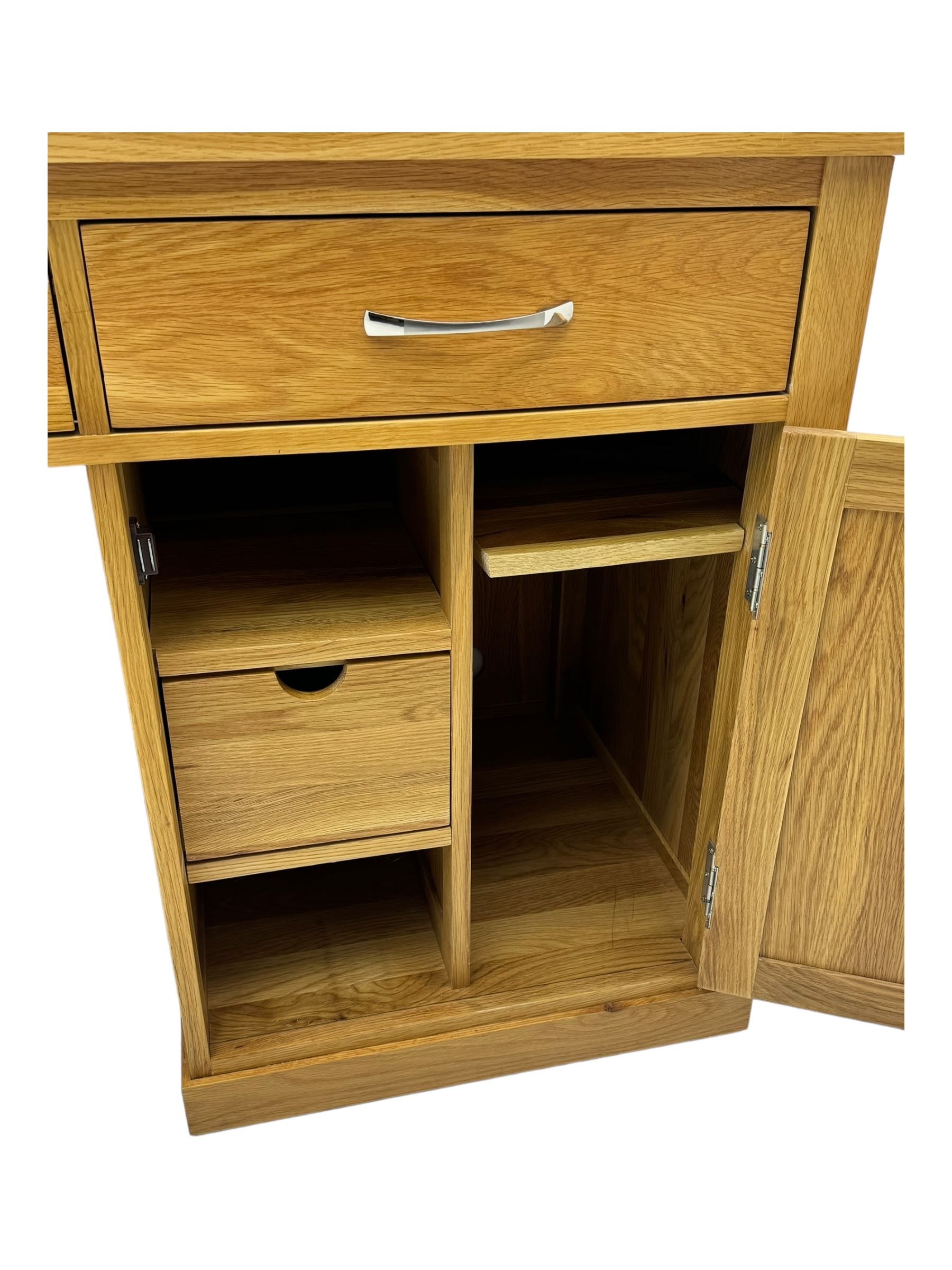 Contemporary light oak twin pedestal desk, fitted with three drawers over two cupboards with chrome handles, the central drawer with hinged front panel revealing pull-out keyboard tray, on plinth base