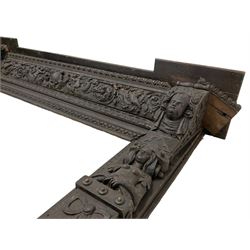 19th century Elizabethan design carved oak fire surround, reverse break-front lintel over egg and dart moulded upper edge, the ovolo-moulded frieze carved with scrolling leafy branches, central cartouche and putti riding dolphins, the uprights carved with female masks over carved busts, square tapering pilasters carved with ribbon tie over trailing fruit, on stepped moulded base 