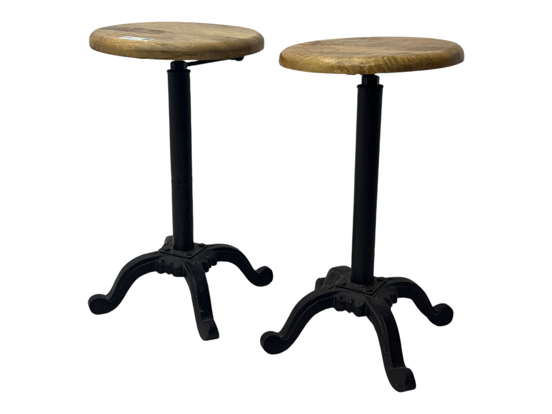 Pair of 20th century machinist stools, each with height-adjustable beechwood circular seats, supported by cast iron pedestal bases with four splayed feet