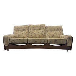 Mid-20th century three-seat sofa with floral patterned upholstery, supported by a sculpted teakwood frame with curved cutout detailing, loose cushioned back and seat, on tubular metal feet