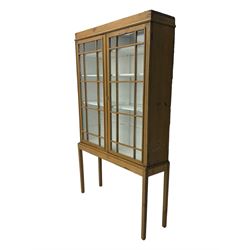 Georgian stripped pine bookcase display cabinet, plain moulded cornice over two glass-panel doors with multiple panes, enclosing white painted interior with three shelves, raised on square supports