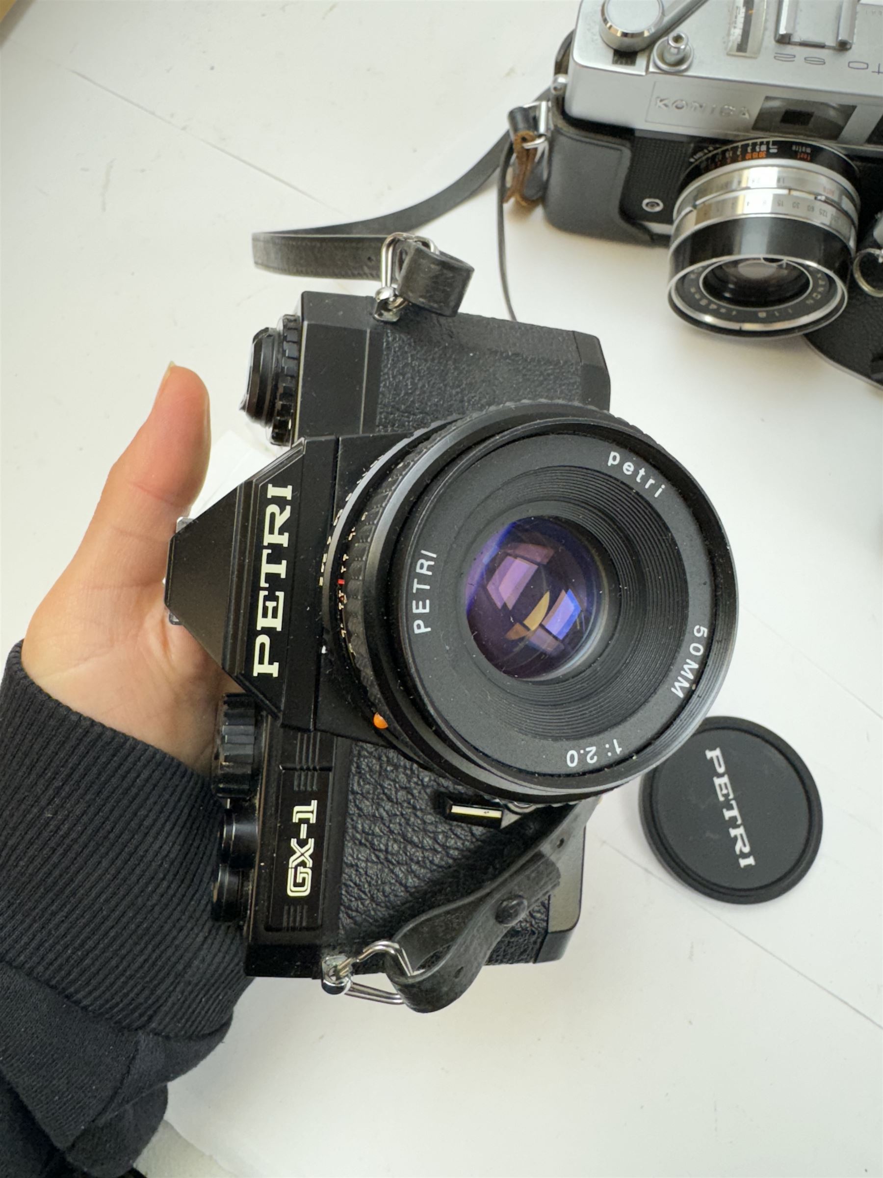 Five SLR cameras, to include Rolleiflex SL35, with a Rollei-HFT Planar 1.8/50 lens serial no. 1246774, Topcon Uni serial no. 5417650, with a Topcor Kogaku UV 1:2 f=53mm lens serial no. 5413035, Bell & Howell Auto35/Reflex Design 237, with a Canon EX 50mm 1:1.8 lens serial no. 92960, Petri GX-1 serial no. 91206945, with a Petri 50mm 1:2.0 lens serial no. 91107428, and a Konica Auto 52 serial no. 1193641, with a Konica Hexanon 1:1.8 f=45mm lens, all in cases 