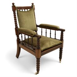 Late Victorian walnut bobbin turned armchair, curved cresting rail with bead moulding over turned spindle back, upholstered arms on turned balustrade supports, cane work seat over seat rail with matching bead moulding, loose seat cushion upholstered in olive green fabric, on tapering bobbin turned front supports with brass and ceramic castors, 