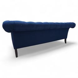 Chesterfield three-seat sofa, traditional shape with rolled arms, upholstered in deep blue buttoned fabric, on black finish turned front feet 