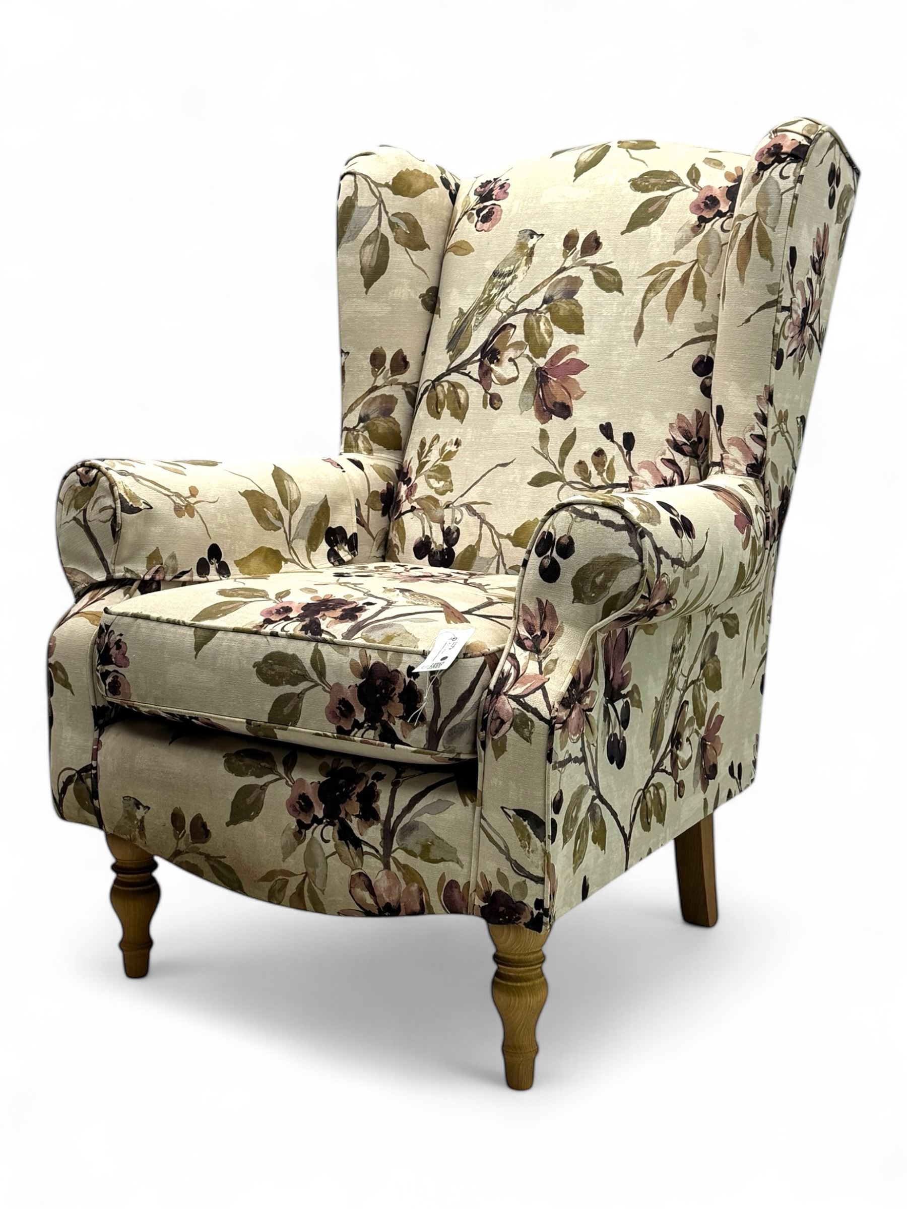 Hardwood-framed wingback armchair, upholstered in cream floral pattern fabric, on turned front feet