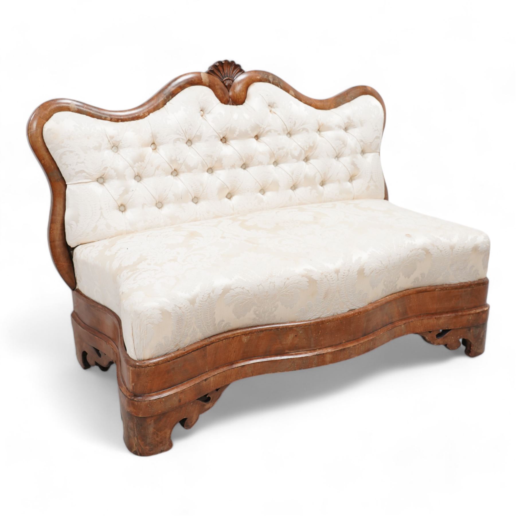 Victorian mahogany frame settee, shaped cresting rail with fan carved cresting, upholstered in buttoned cream fabric with repeating floral pattern, low serpentine seat, shaped and pierced bracket feet, on brass castors 