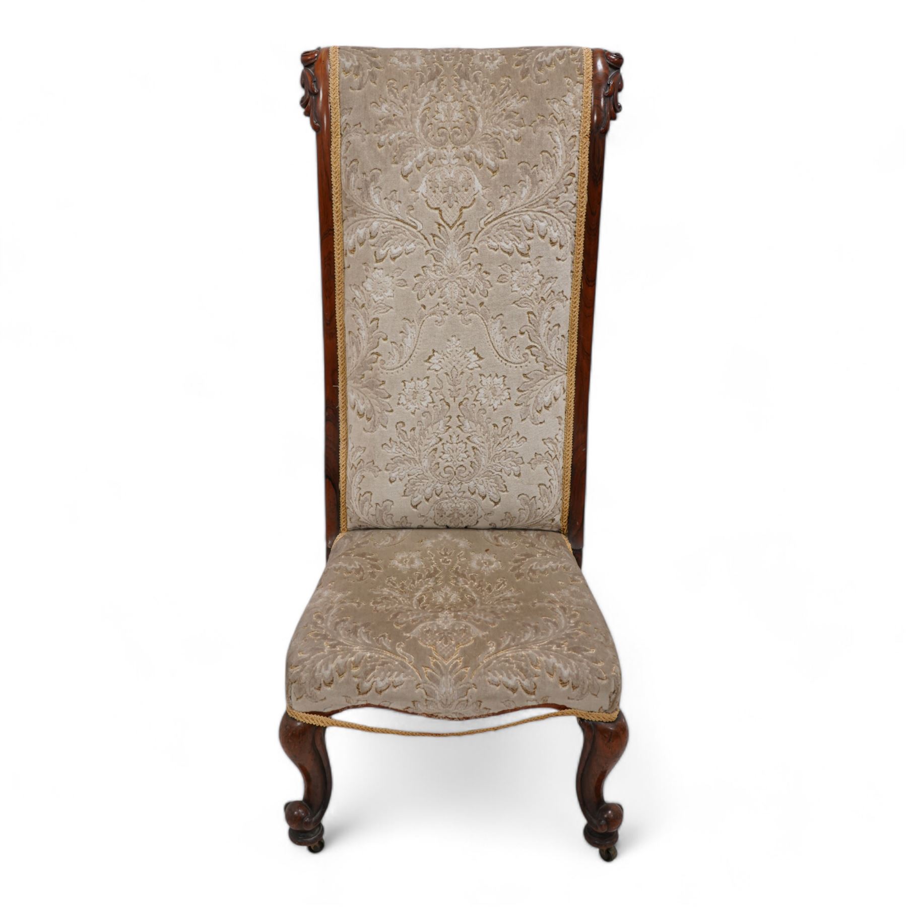 Victorian rosewood prie dieu chair, the ears carved with curl leaves, upholstered in foliate pattern fabric, cabriole feet on brass castors 