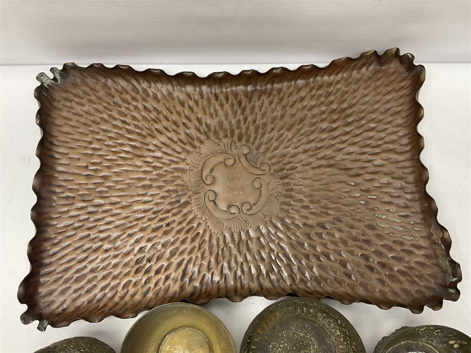 Beaten copper tray with repeat pattern and fluted rim, together with six brass cups, tray L41cm 