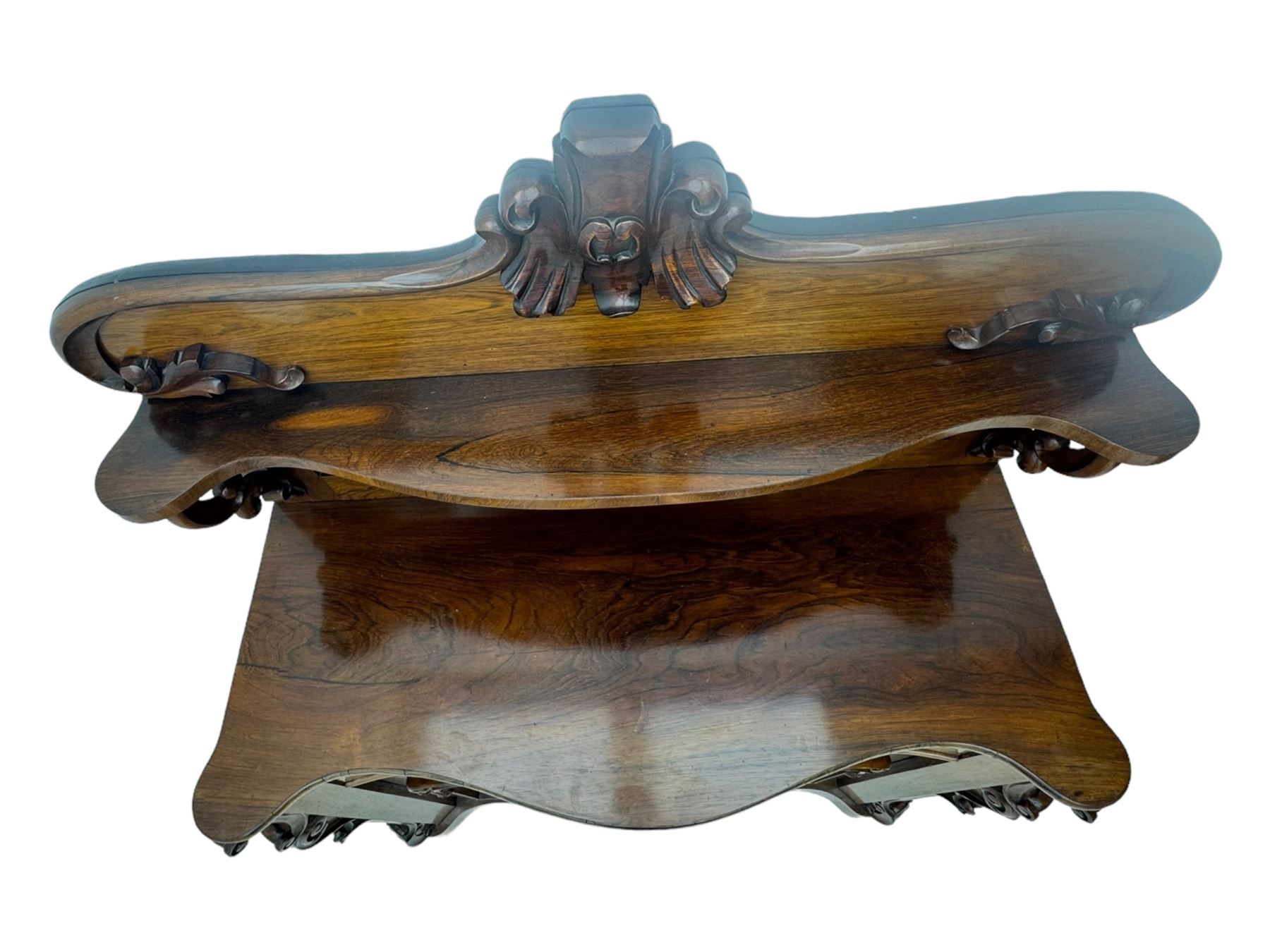 Mid-19th century rosewood chiffonier, raised back with scroll and leaf carved shaped pediment, serpentine top over drawer and double cupboard with scrollwork decoration, on shaped plinth base