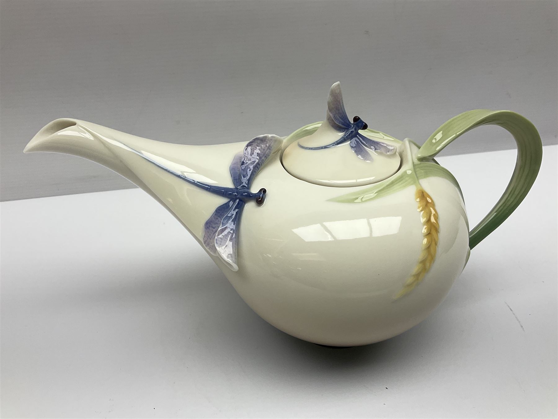 Franz Teapot decorated with dragonflies, together with a matching sucrier and cover and a cup and saucer in Iris pattern, all with printed mark beneath 