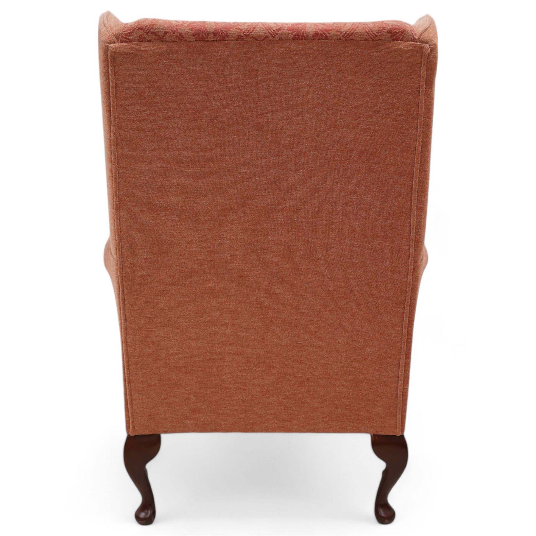 Hardwood-framed wingback armchair, upholstered in peach fabric, on cabriole feet 