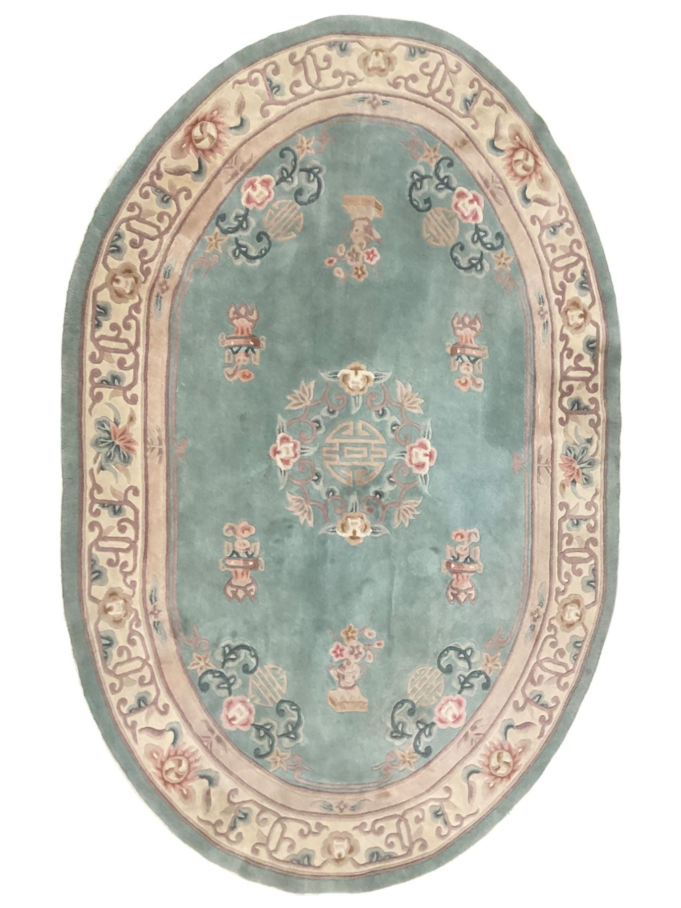 Chinese pale turquoise ground washed woolen rug, oval form decorated with bouquets of floral designs and Chinese characters, enclosed by a wide guard band