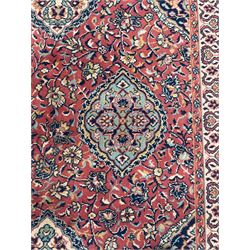 Large Persian design red ground carpet, the field decorated with multiple shaped panels surrounded by trailing leafy branches and stylised plant motifs, the guarded border decorated with shaped panels and floral pattern 