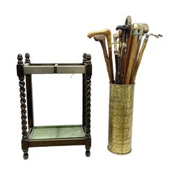 Oak barley twist stick stand, with a collection of walking sticks including examples with carved pommels, horn handles, silver collar etc, together with brass stick stand 