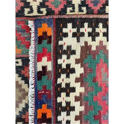 Northeast Persian Sumak Kilim red ground rug, the field decorated with rows of multicoloured diamond motifs featuring  geometric patterns, the border composed of alternating black and white stepped designs, enclosed by a narrow band with multicoloured geometric shapes