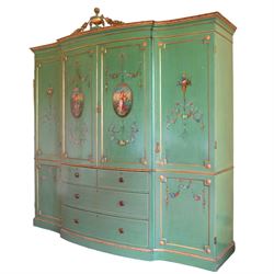 Edwardian Adam Revival break-bowfront quadruple green-painted and parcel gilt wardrobe, the projecting acanthus leaf moulded cornice surmounted by urn with trailing flower heads, two central panelled doors enclosing linen slides, decorated with oval painted panels depicting maidens with flowers and scrolled acanthus leaves with floral festoons, two short and two long drawers below, flanked by full-height panelled doors enclosing hanging rails and hooks, foliate moulded plinth base