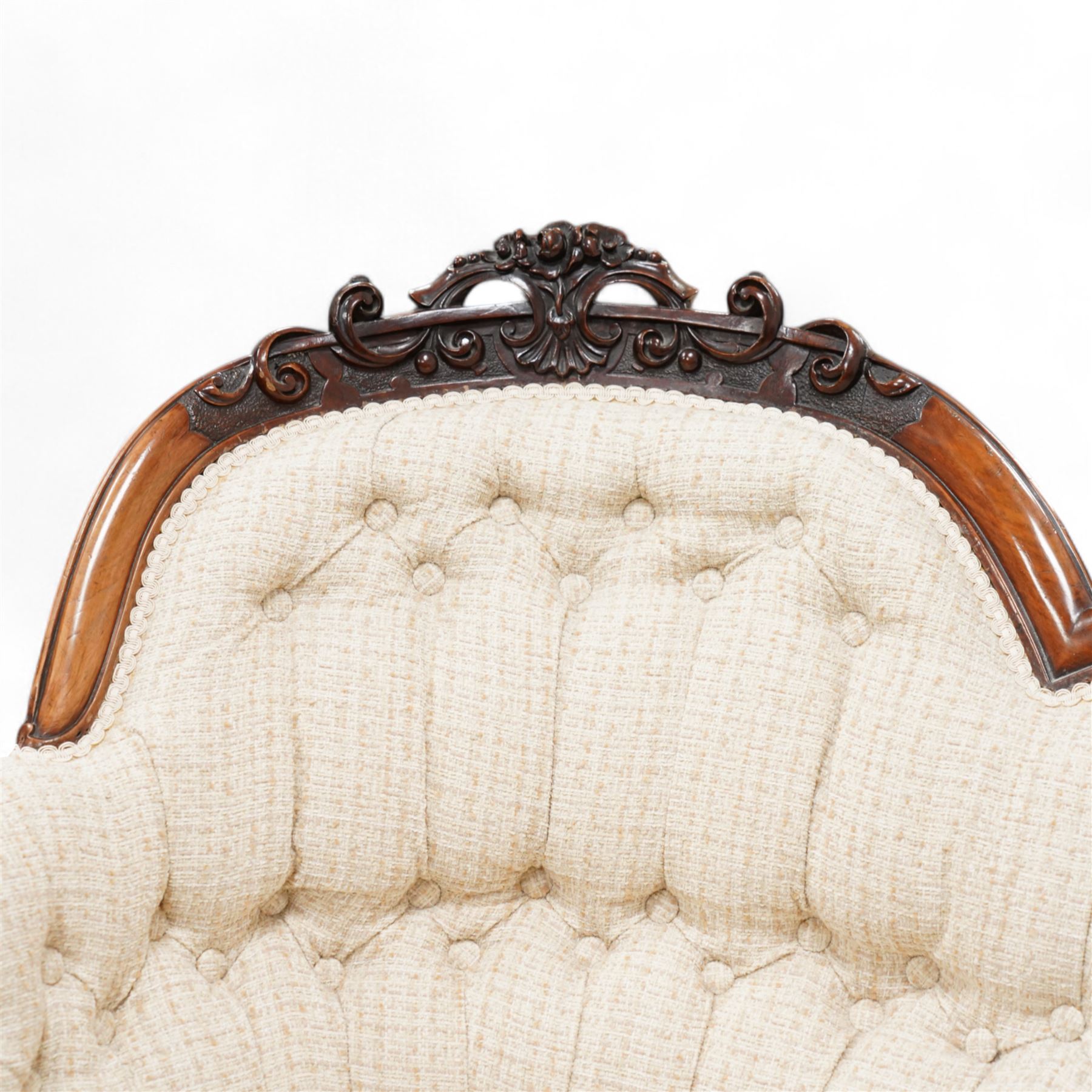 Victorian walnut framed chaise longue, the shaped frame carved with scrolls and flower heads, upholstered in buttoned textured cream fabric, the shaped seat rail carved with flower heads and extending foliate scrolls, on floral carved cabriole feet with castors 