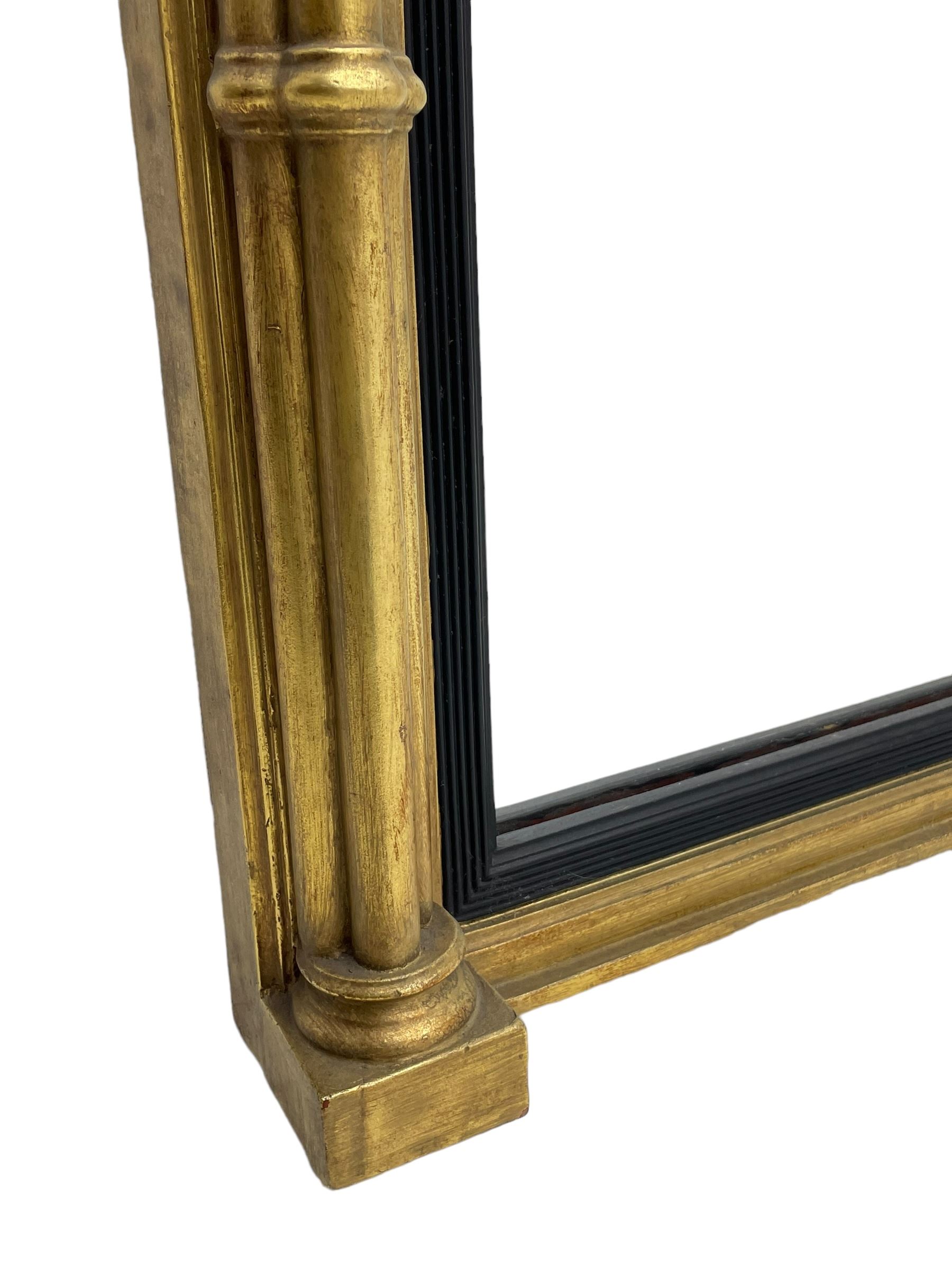 Regency design giltwood overmantel mirror, projecting cornice over pointed arcade frieze and foliate moulded upper edge, plain mirror plate within reed moulded ebonised slip, flanked by cluster columns with acanthus and scroll decorated Composite order capitals 