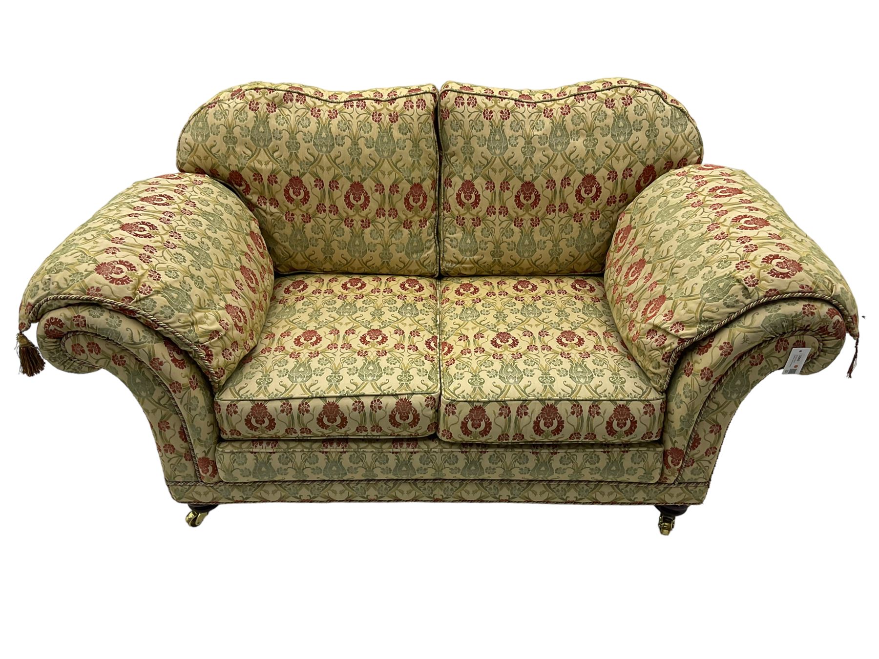 Traditional design two seat sofa, high back with scrolled arms, upholstered in beige fabric with red and green damask motifs, on castor supports (L178cm, D100cm, H89cm); matching armchair (L109cm, D89cm, H89cm)