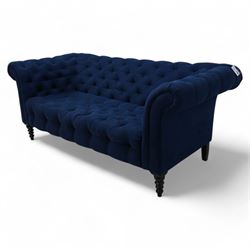 Chesterfield two-seat sofa, traditional shape with rolled arms, upholstered in deep blue buttoned fabric, on black finish turned front feet 