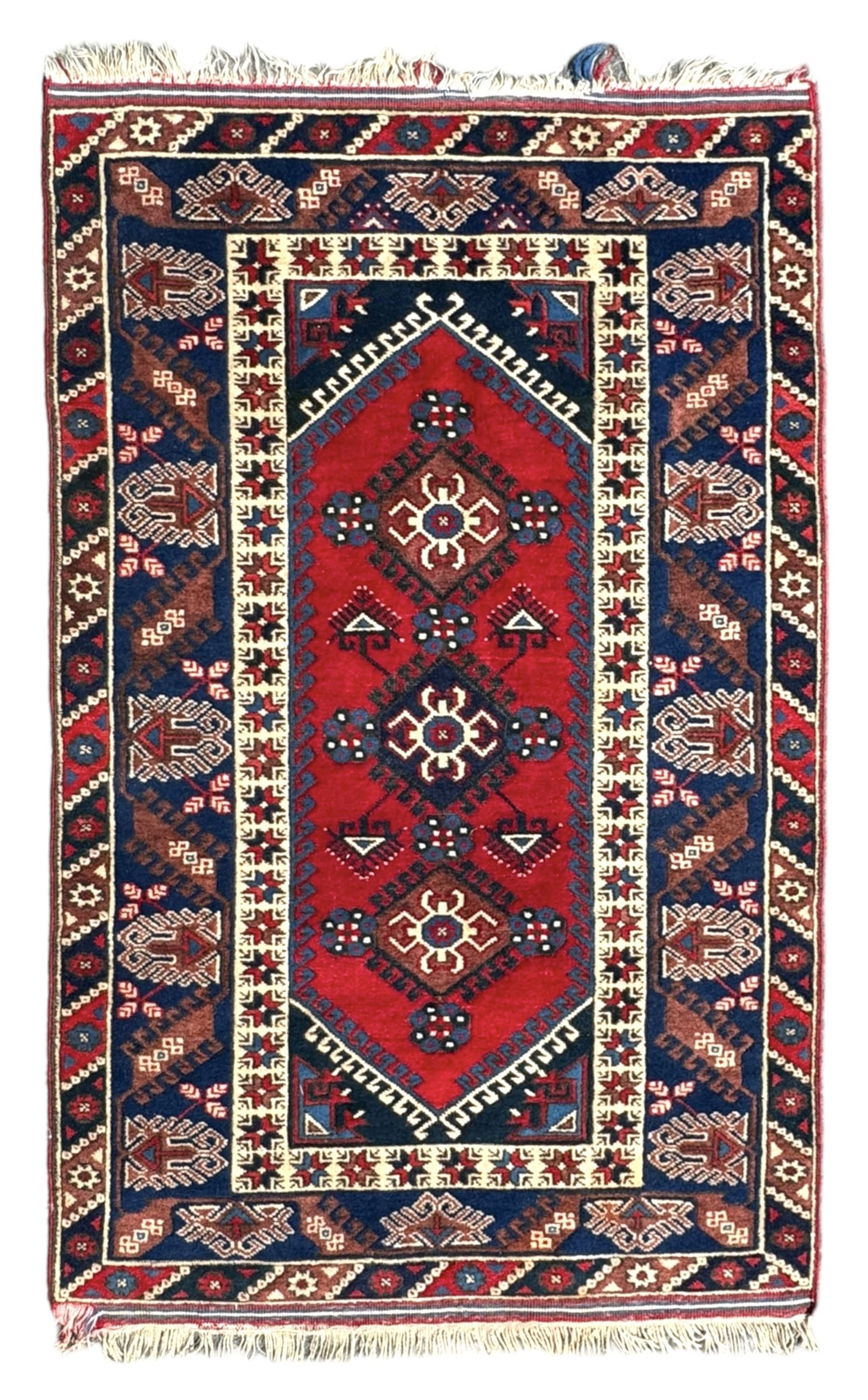 Turkish crimson ground rug, the field decorated with three geometric medallions within a band of star motifs, the main border decorated with stylised plant motifs 